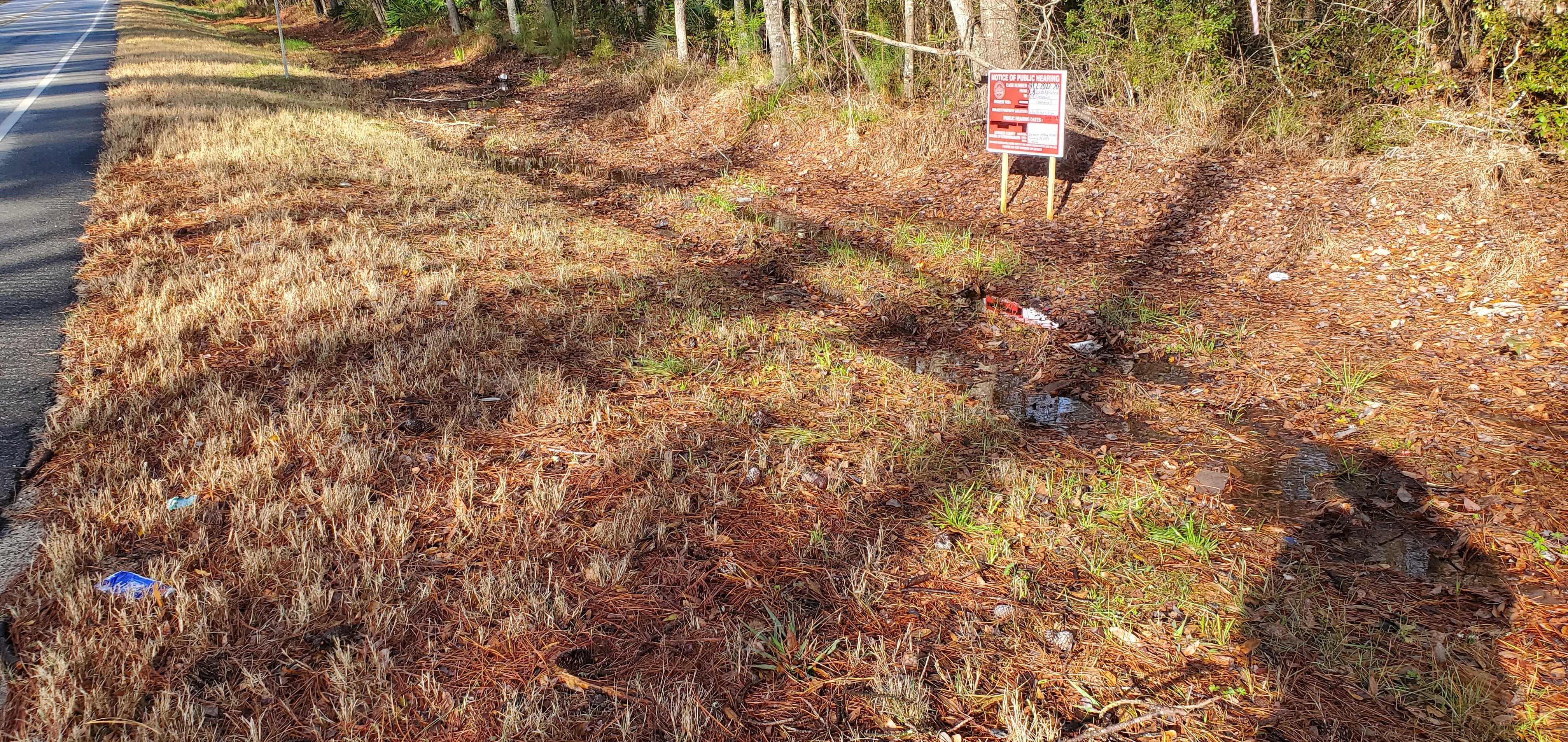 Trash in the ditch next to the sign